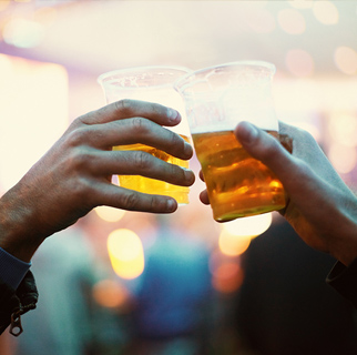 close up image of of two glasses of beer clinking together.