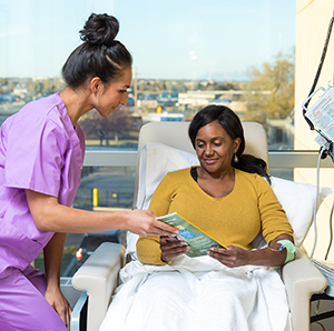 Healthcare provider caring for woman having infusion treatment.