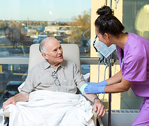 Healthcare provider caring for man having infusion treatment.